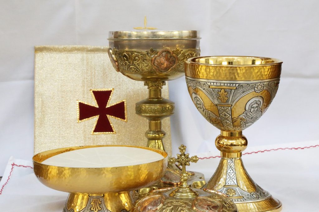 Eucharystia - dwa złote kielichy z winem i chleb. Obok krucyfiks